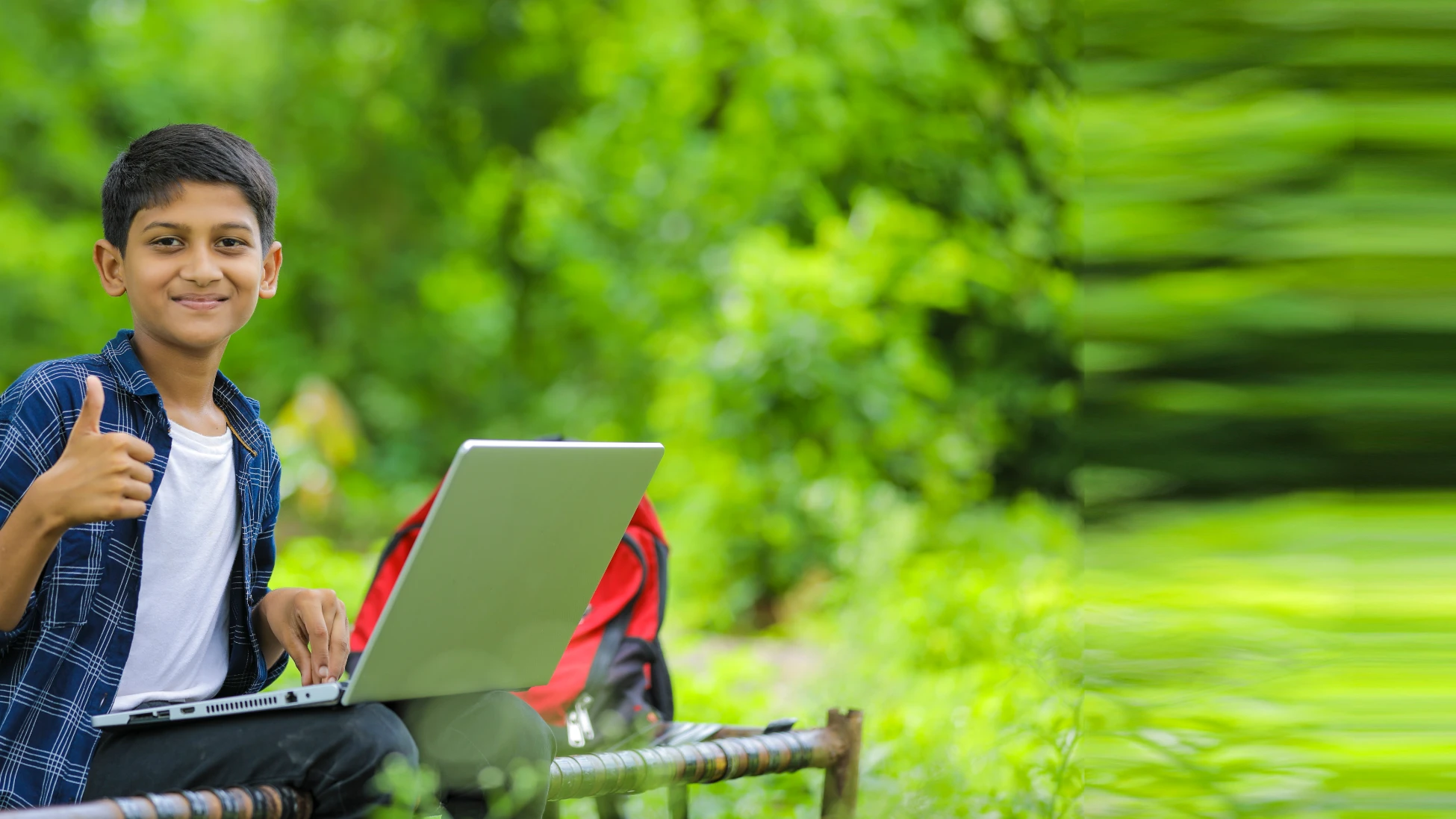An open laptop resting on grass in a green outdoor setting