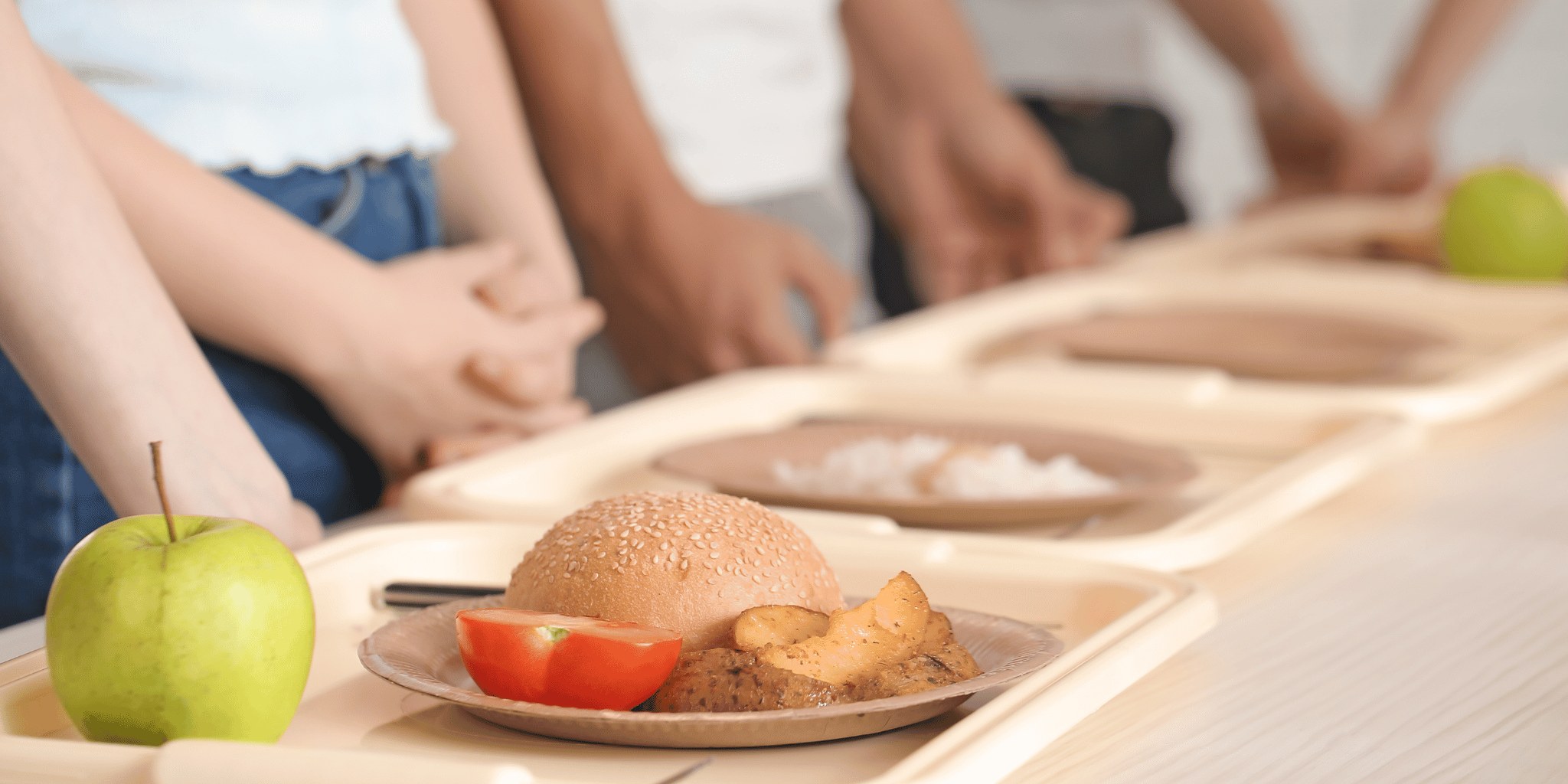 A school lunch tray holding a bread roll and an apple