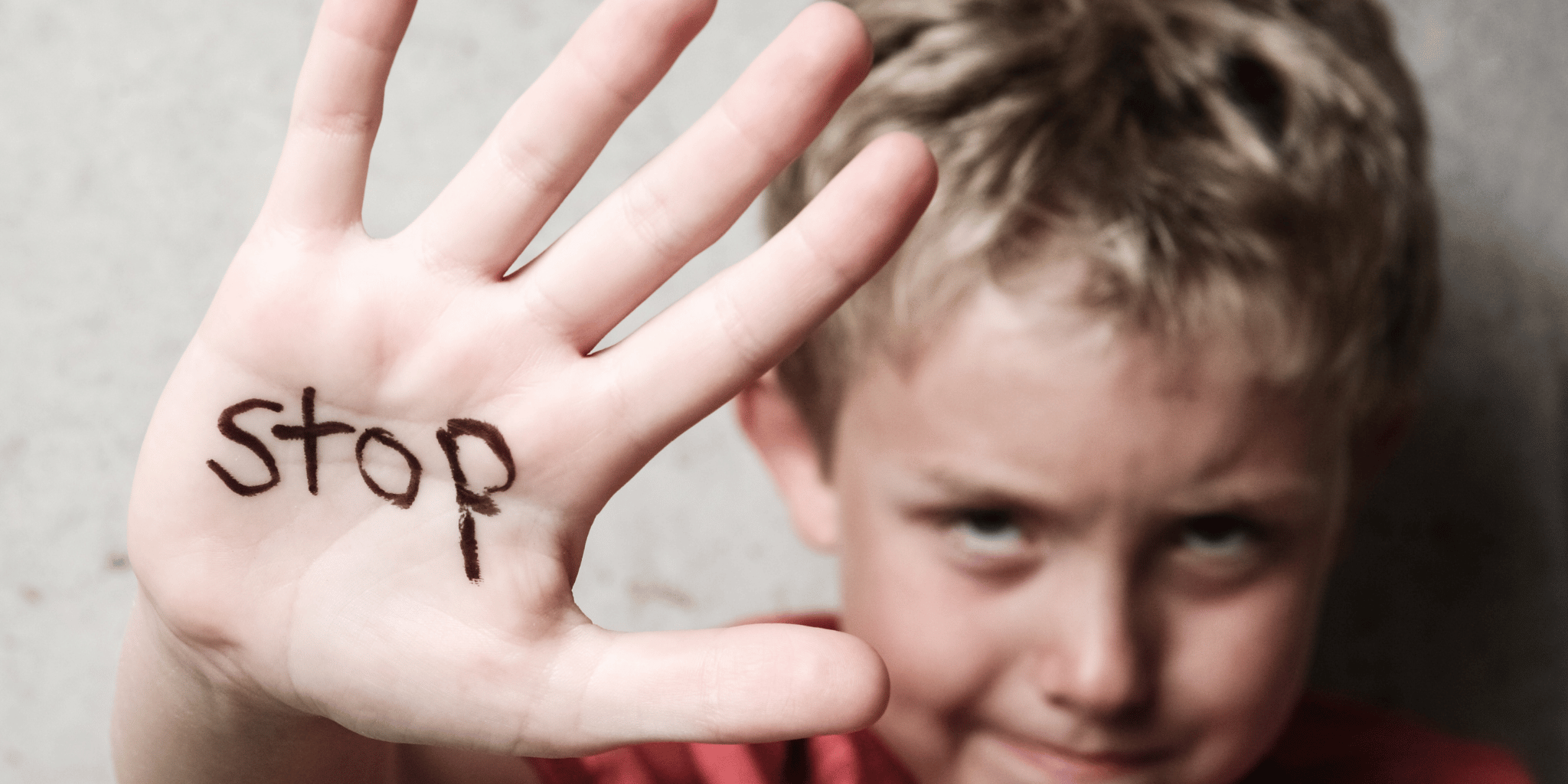A boy holding up his palm with the word stop written on it