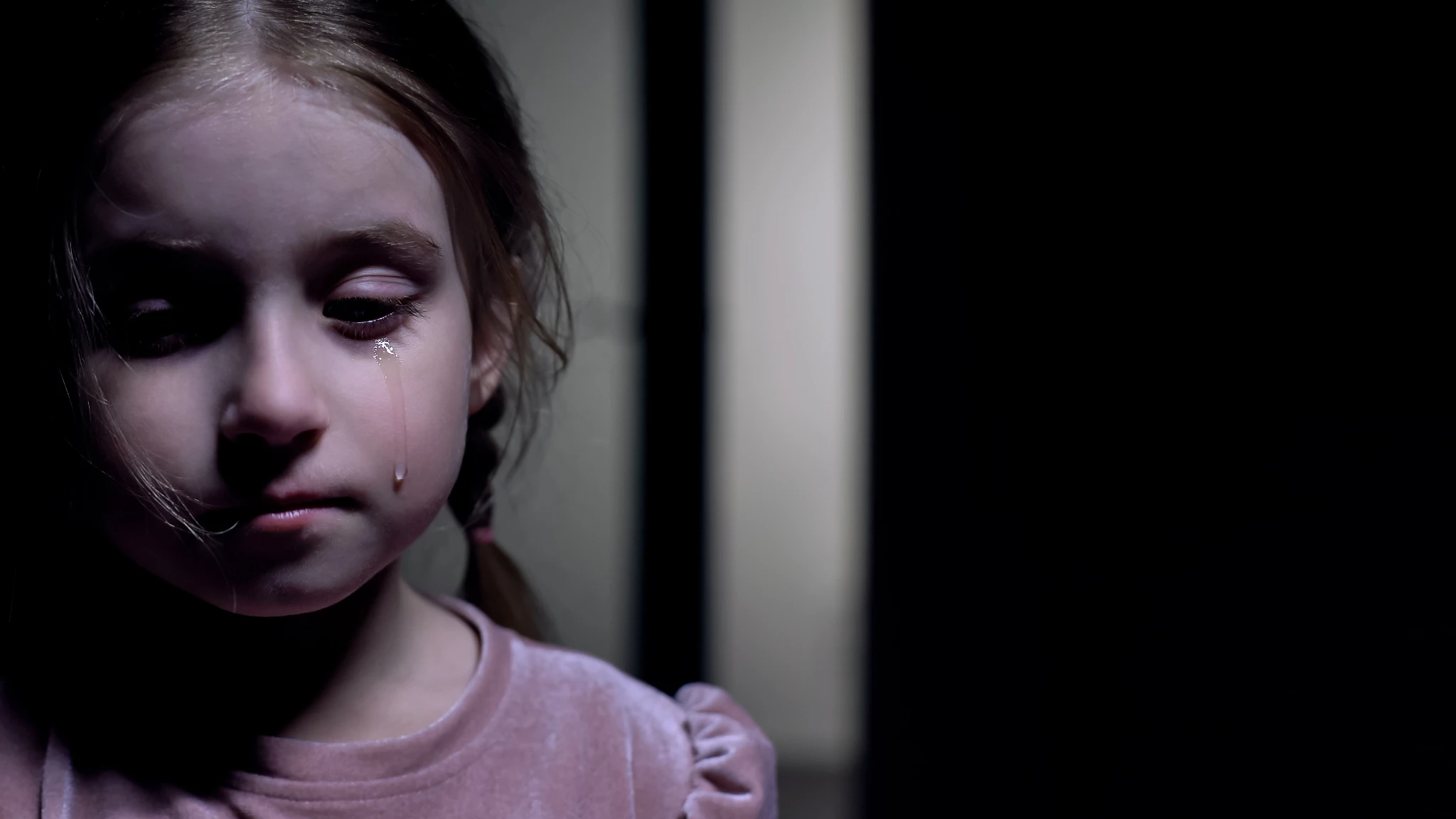A girl's face lit in a darkened room