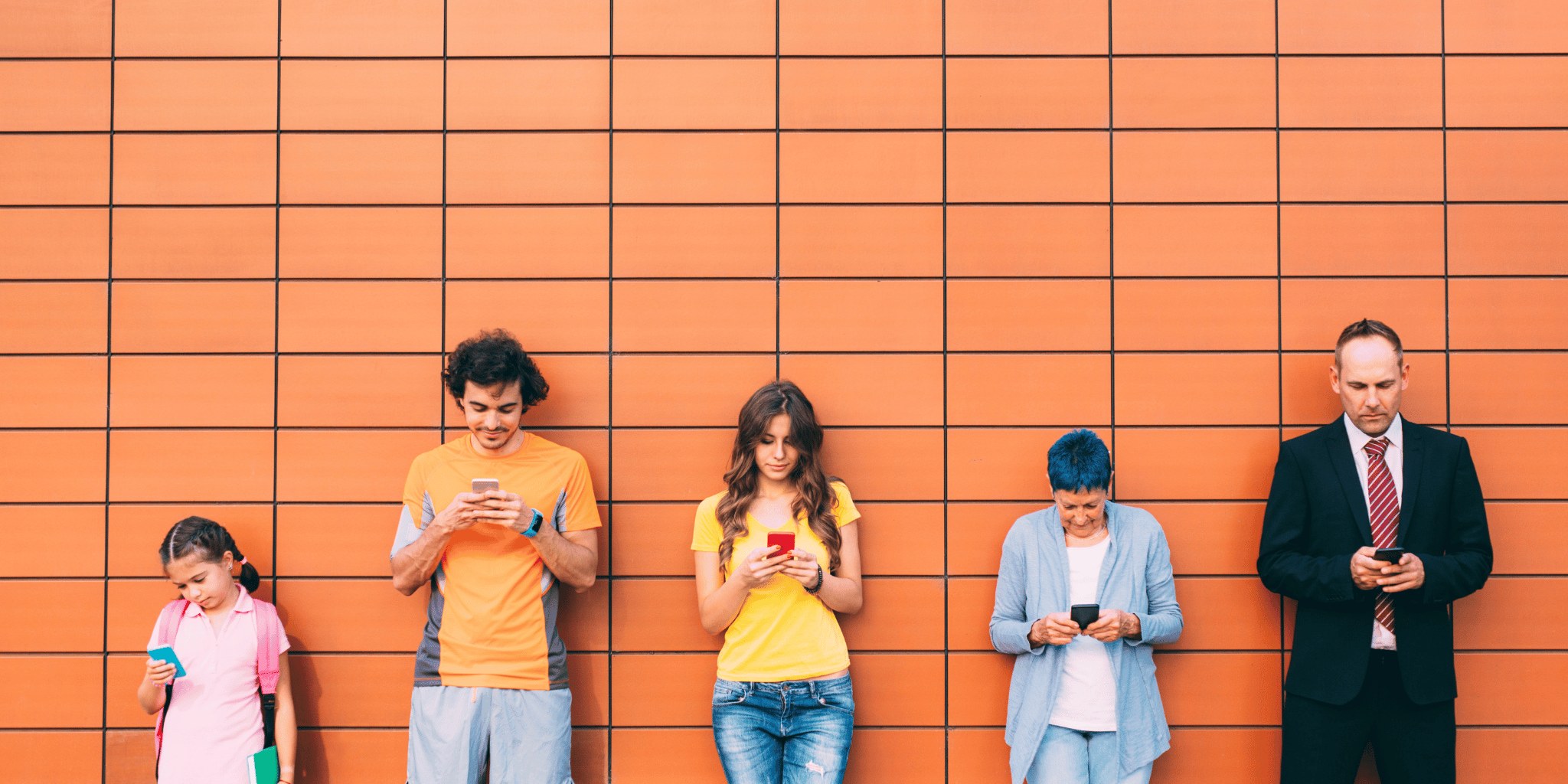 A group of people standing in front of an orange brick wall