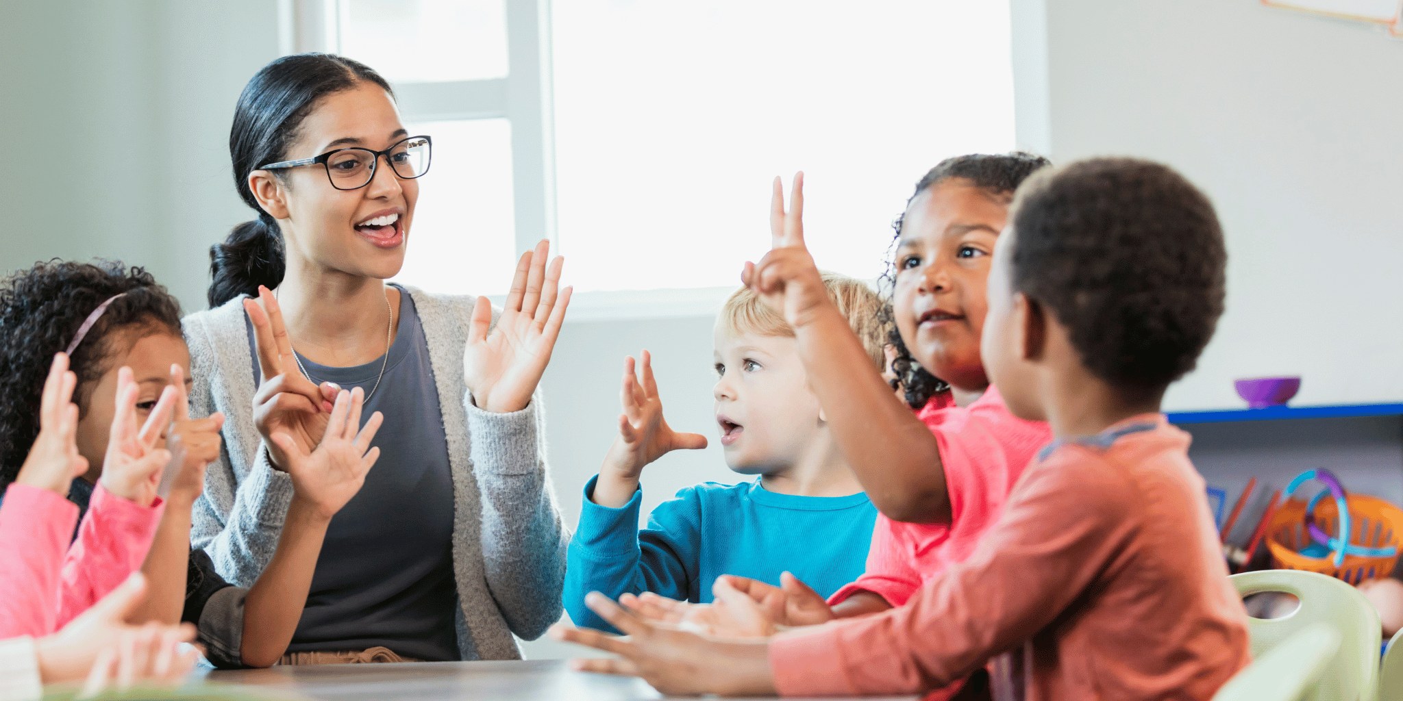 A woman clapping along with children in a classroom
