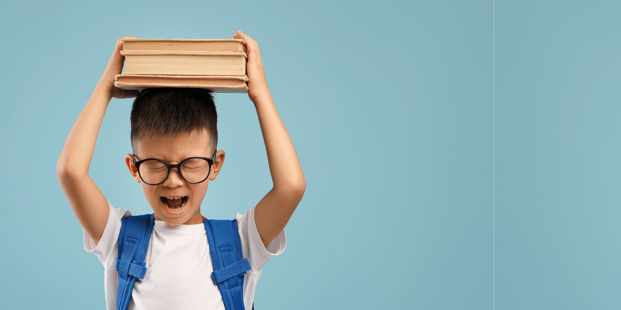 A boy in glasses balancing a stack of books on his head