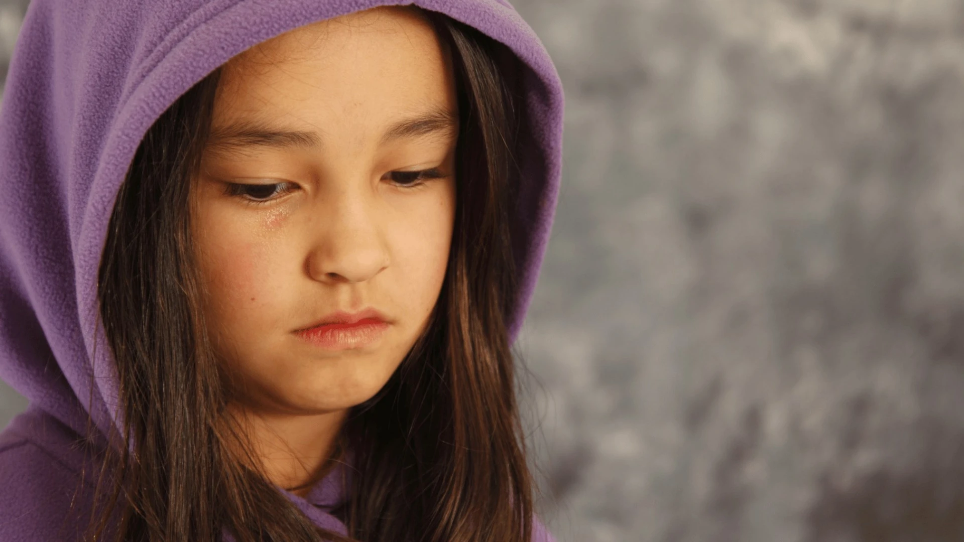A girl in a purple hood looking sad